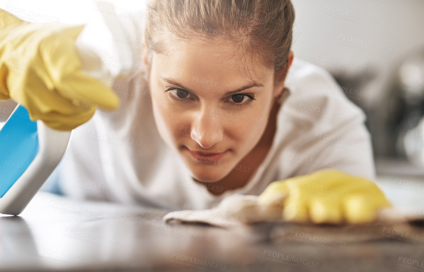 Buy stock photo Cleaning, focus and a woman wiping a table of dust or bacteria for housework. Serious, bottle and a young lady or cleaner spraying a liquid to clean a desk or counter in a house for housekeeping