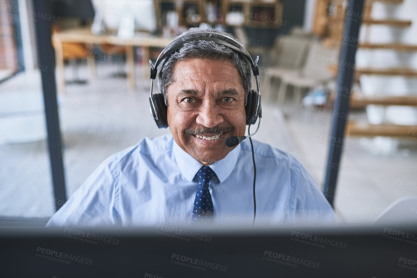 Buy stock photo Portrait of a cheerful businessman talking to a customer using a headset while looking at the camera