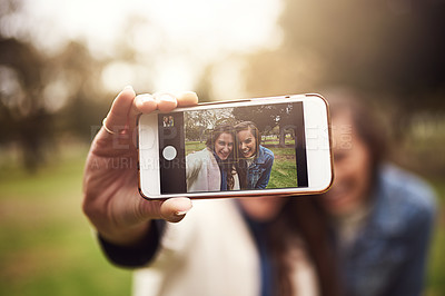 Buy stock photo Shot of two cheerful young friends taking a self portrait together outside in a park
