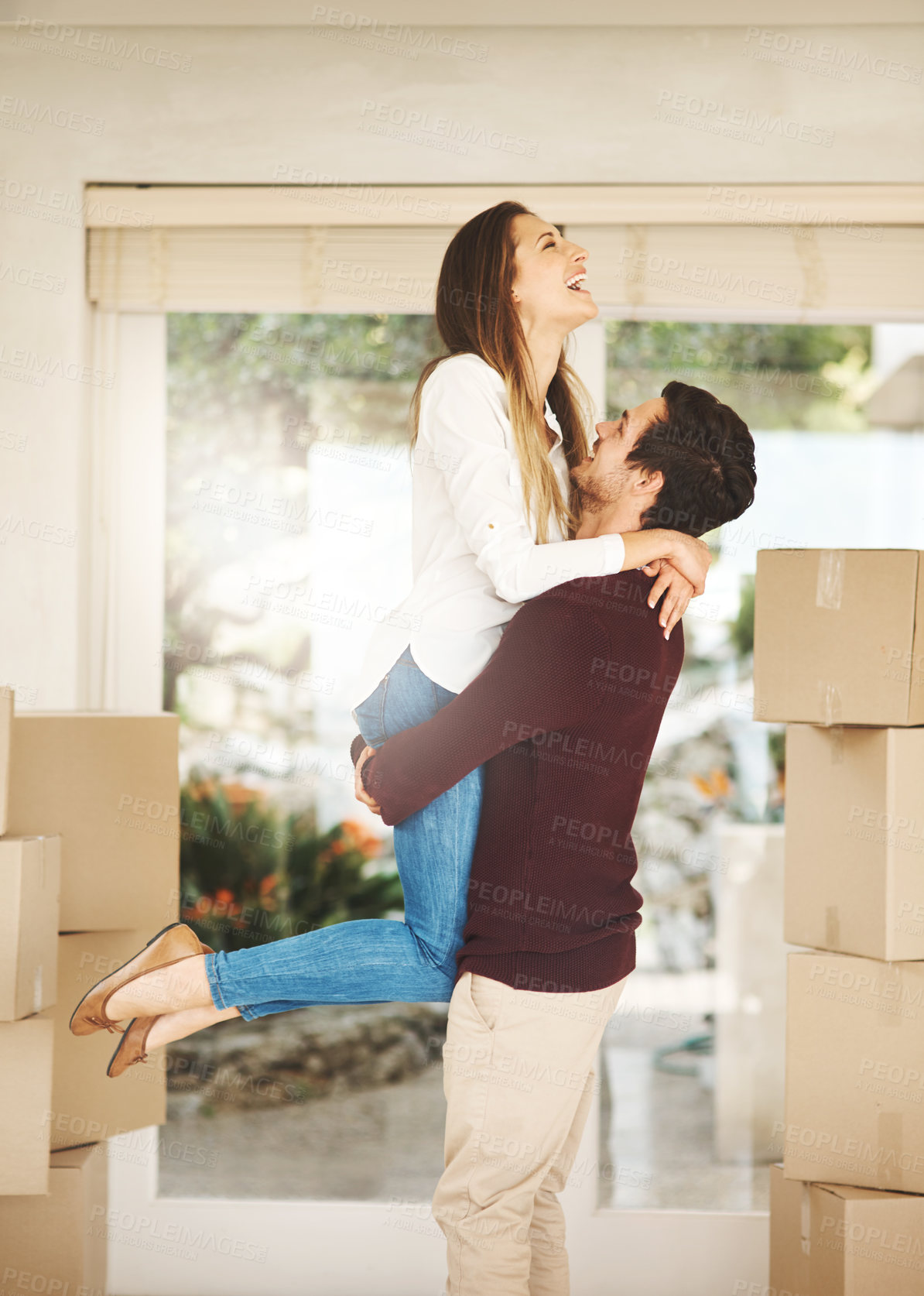 Buy stock photo Cropped shot of an affectionate young couple embracing while moving into a new home