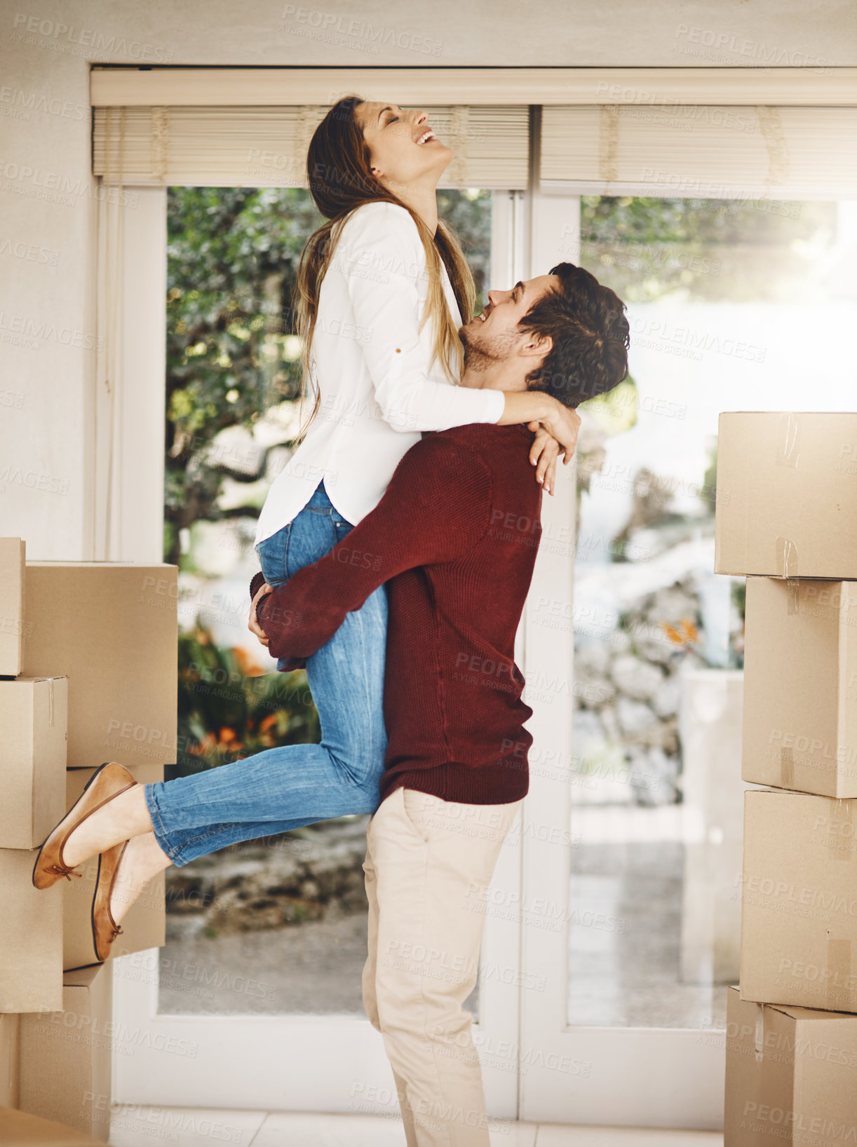 Buy stock photo Cropped shot of an affectionate young couple embracing while moving into a new home