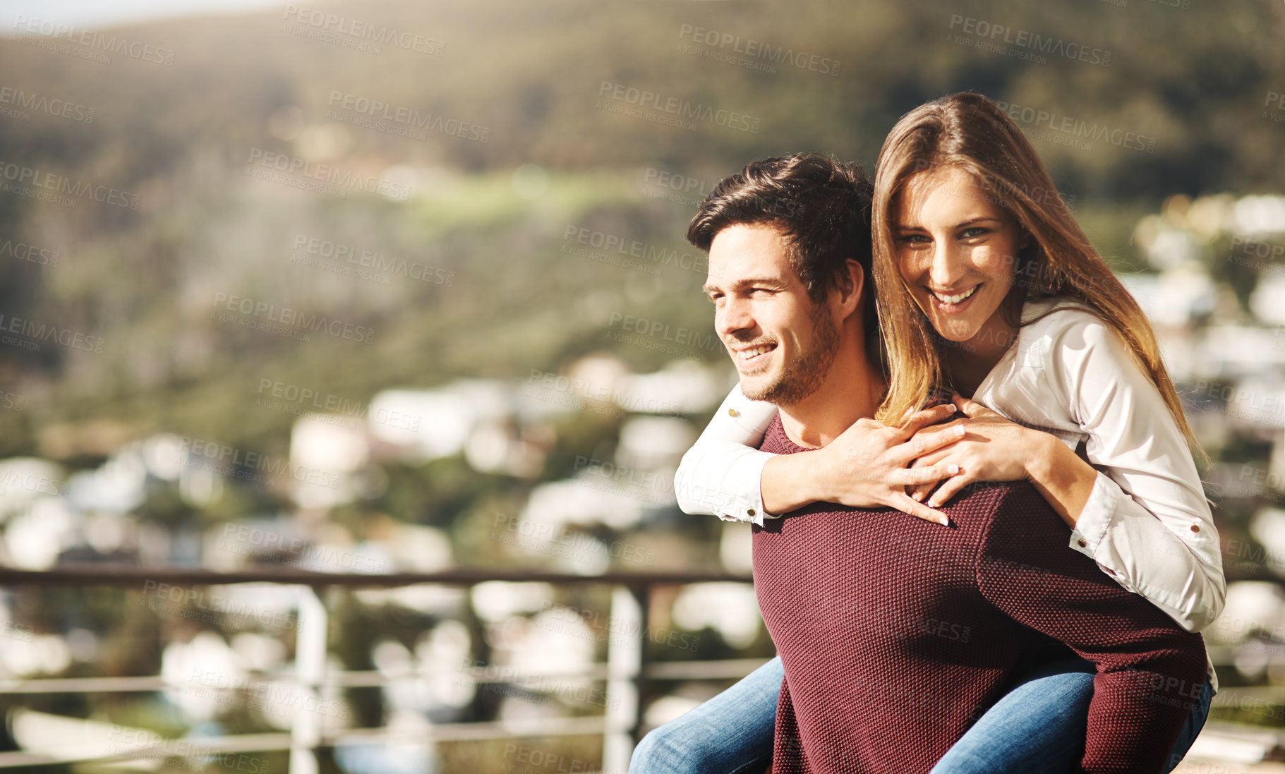 Buy stock photo Cropped shot of a handsome man carrying his girlfriend on his back on their balcony