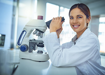 Buy stock photo Portrait of a young scientist using a microscope in a lab