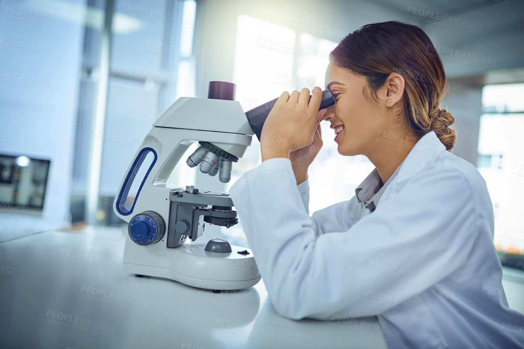 Buy stock photo Shot of a young scientist using a microscope in a lab