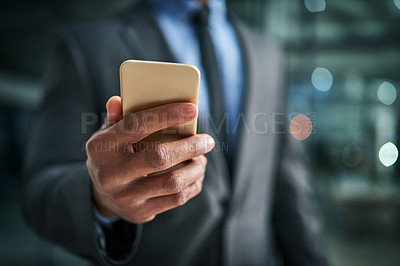 Buy stock photo A phone in hand for texting, communication and networking for business planning, discussion and strategy. Closeup of a corporate professional holding a cellphone while standing on a dark background