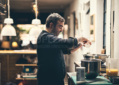 Buy stock photo Shot of a focused chef preparing a dish in the kitchen of a restaurant