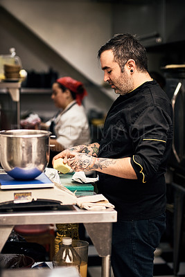 Buy stock photo Shot of a focused chef preparing a dish in the kitchen of a restaurant