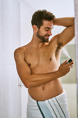 Buy stock photo Shot of a handsome young man applying antiperspirant at home