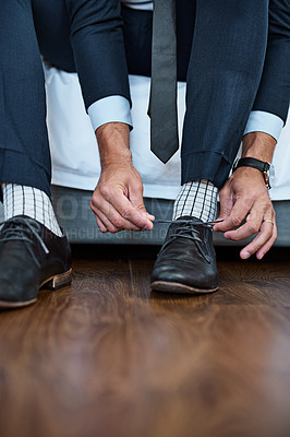Buy stock photo Shot of an unrecognizable man tying his shoelaces at home