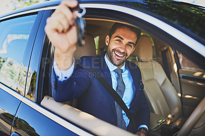 Buy stock photo Portrait of a cheerful young businessman holding up keys to the camera while being seated in his car