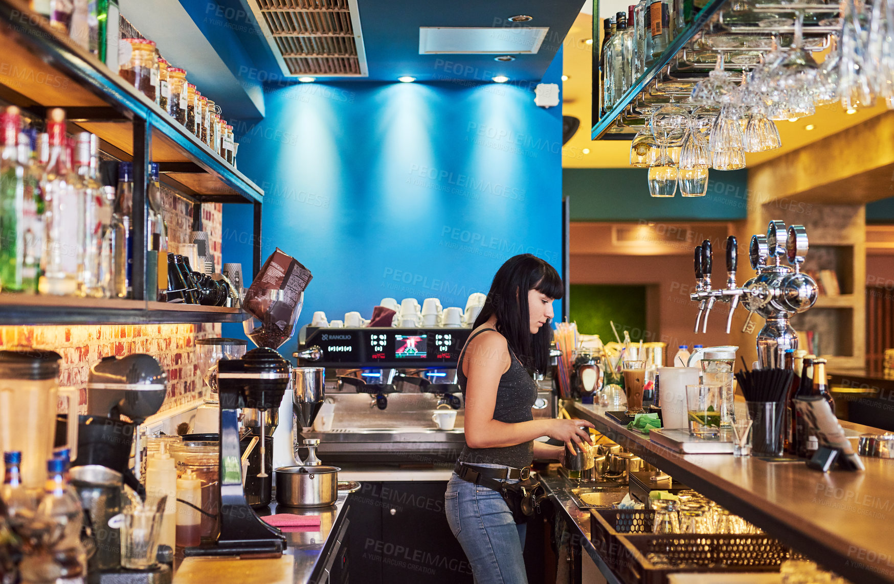 Buy stock photo Shot of a young waitress working behind the counter at a bar