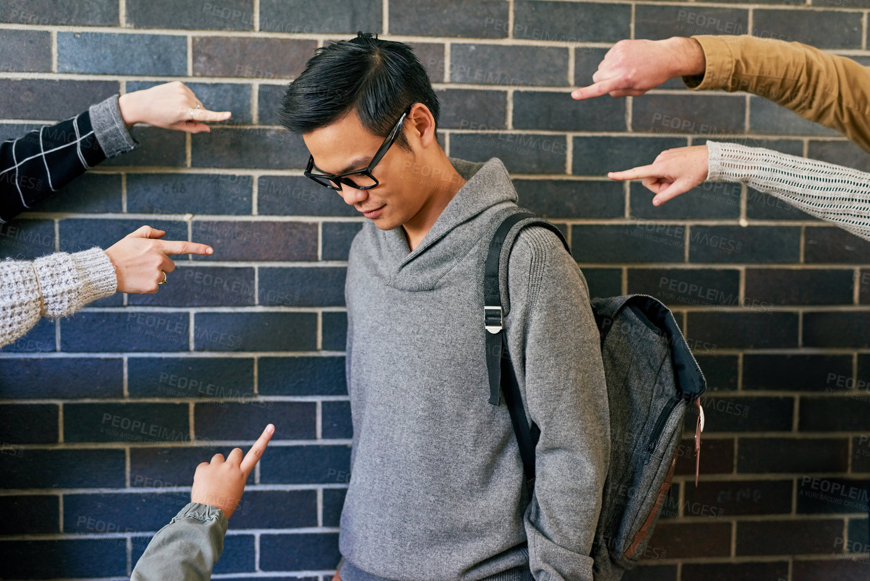 Buy stock photo Cropped shot of a young male university student being bullied while standing in a campus corridor