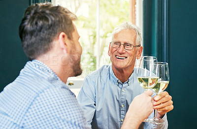 Buy stock photo Shot of a cheerful elderly man and his son sharing a celebratory toast with wine glasses at home