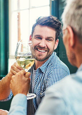 Buy stock photo Shot of a cheerful young man and his mature father having a celebratory toast with wine glasses at home