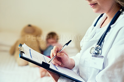 Buy stock photo Cropped shot of a doctor filling out a form while treating a child patient