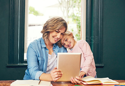 Buy stock photo Shot of a cheerful young aged mother and her young little daughter playing around on a digital tablet at home