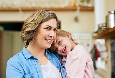 Buy stock photo Portrait of a cheerful young mother holding her young little girl in her arms in the kitchen at home