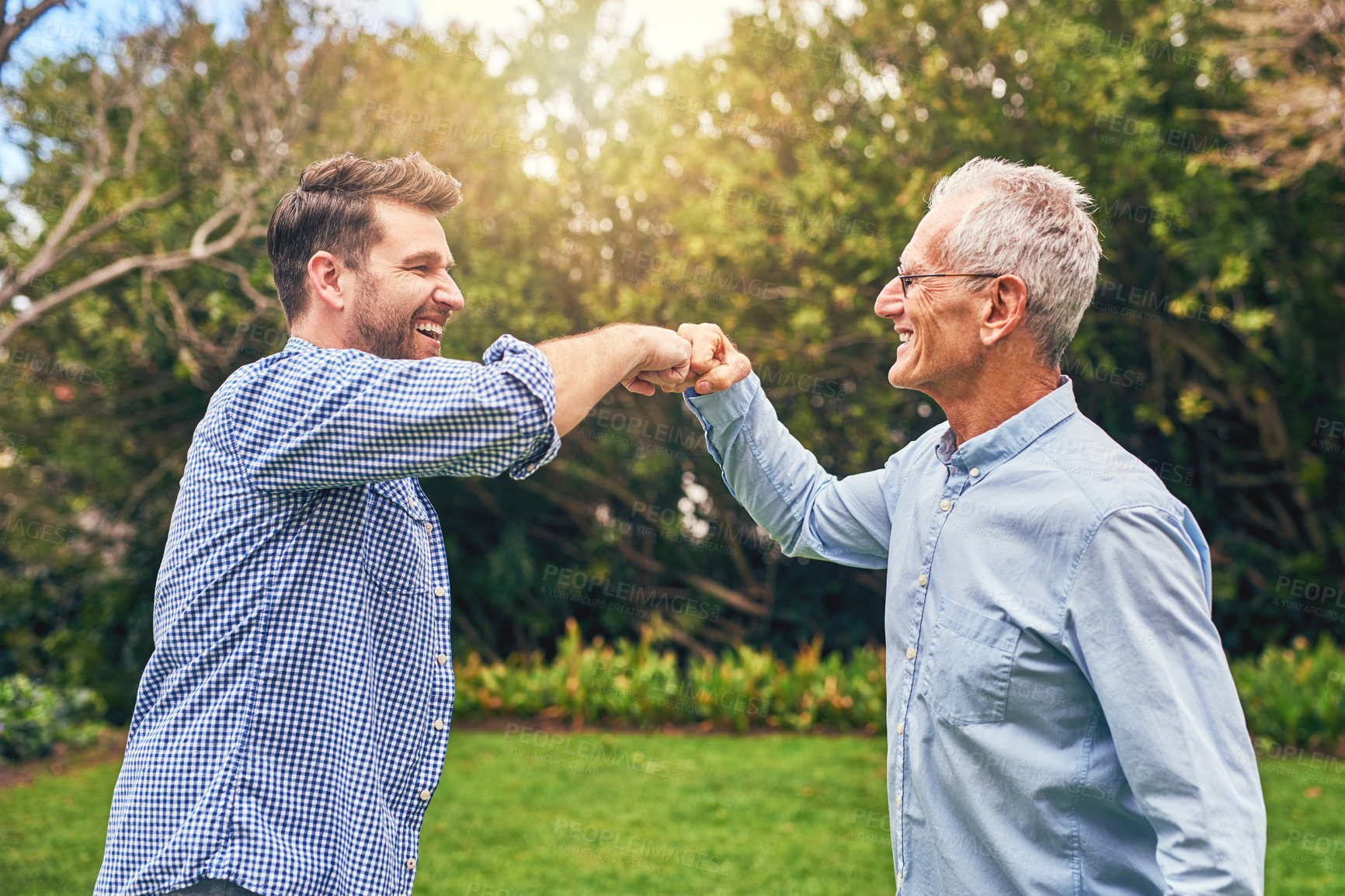Buy stock photo Shot of a senior father and his adult son giving each other a fist pound outside