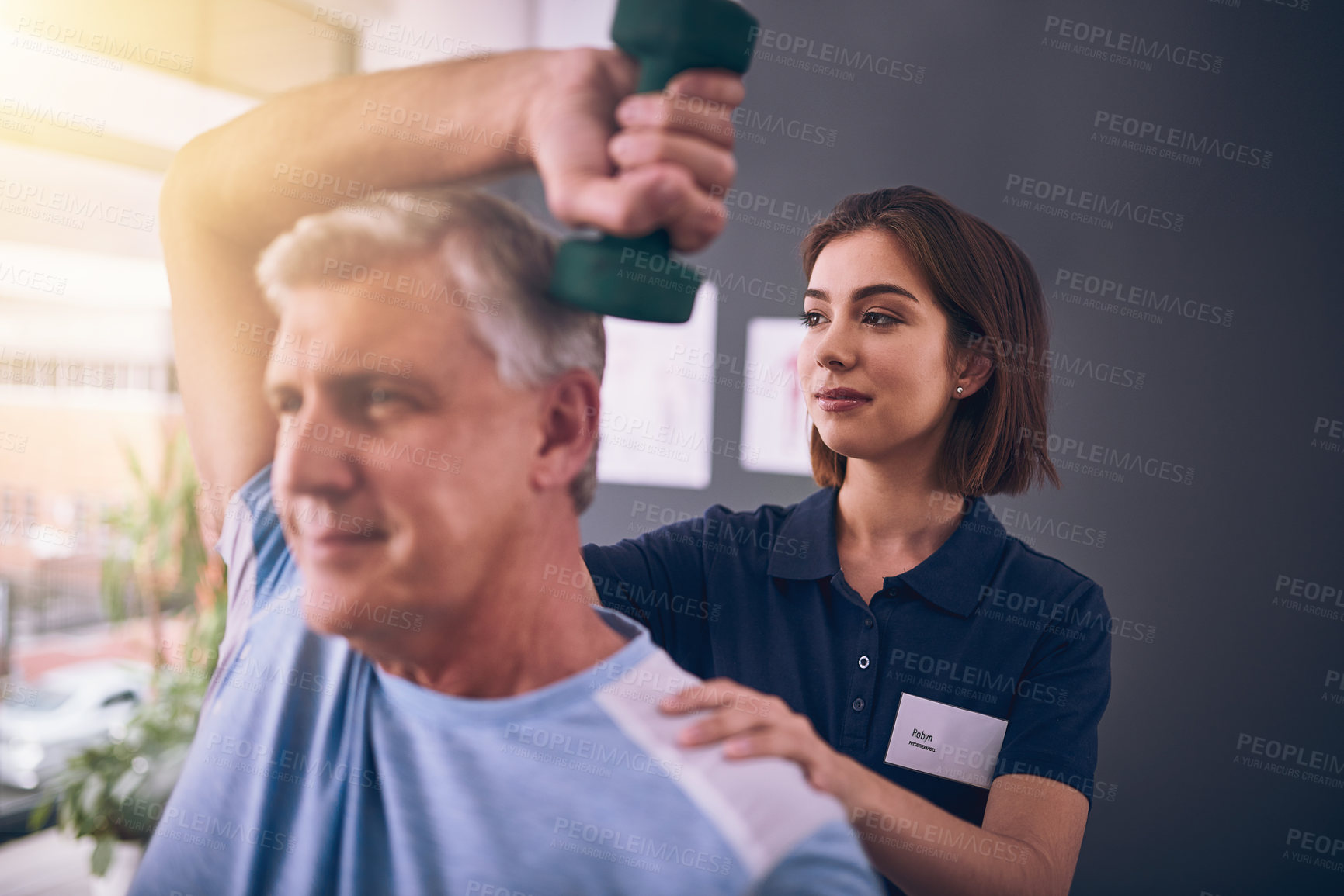 Buy stock photo Physiotherapist, old man and dumbbell for recovery at clinic, rehabilitation and specialist for help. Woman, chiropractor and patient for injury consultation, weightlifting and support with treatment