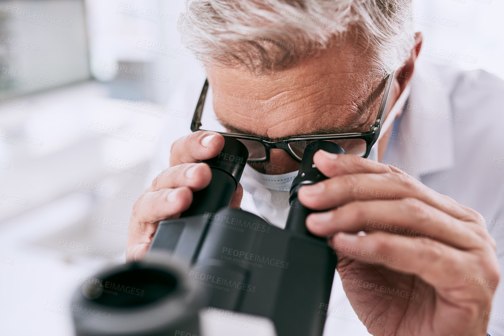 Buy stock photo Shot of a mature scientist using a microscope in a lab