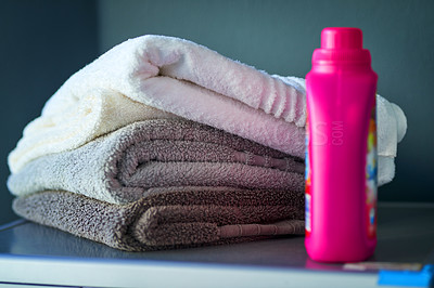 Buy stock photo Laundry, stack and clean towels with bottle for hygiene, washing machine or housework. Cloth pile, fabric softener and detergent for chores, chemical and fresh folded textile in home bathroom closeup