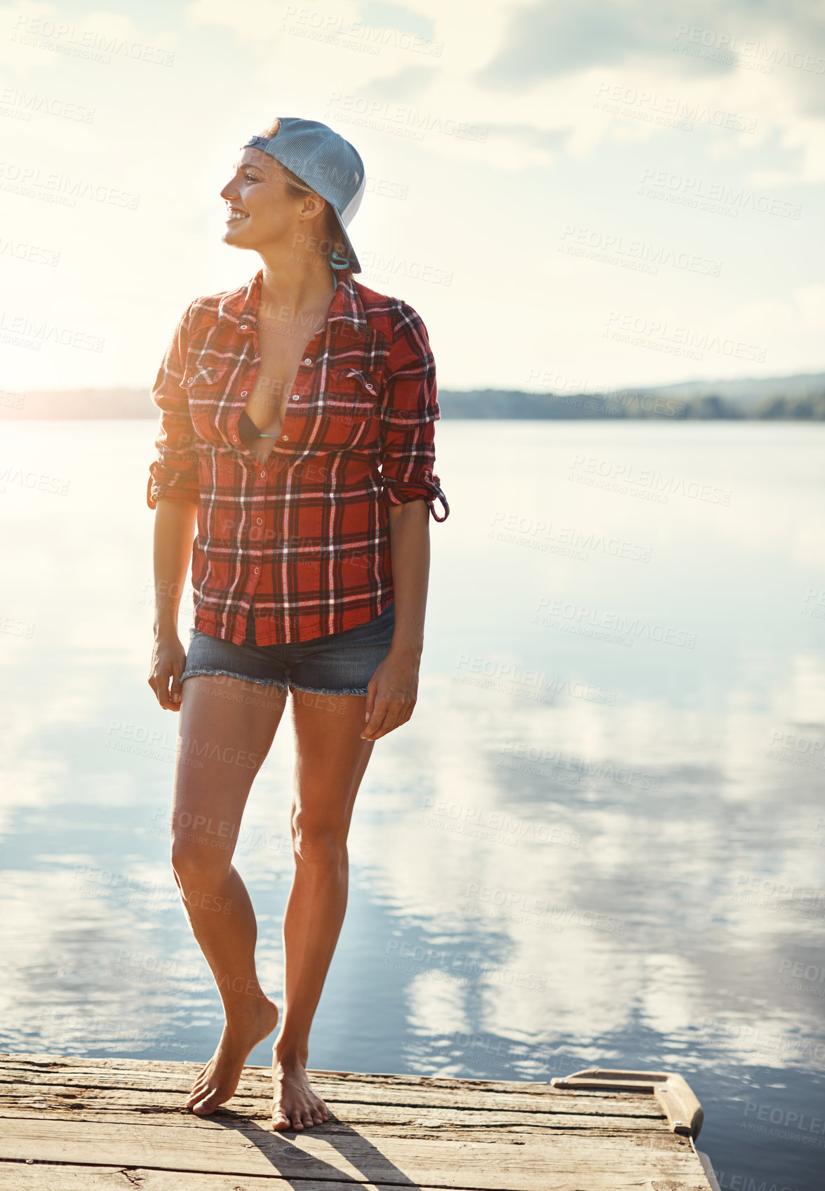 Buy stock photo Shot of a happy young woman spending time by the lakeside