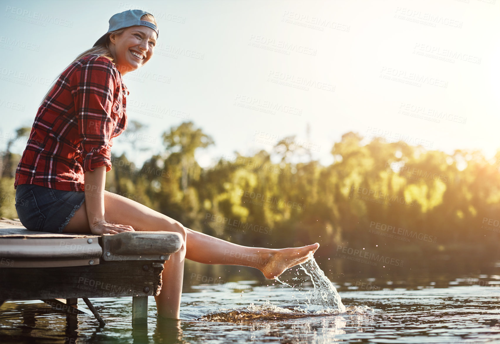 Buy stock photo Shot of a happy young woman spending time by the lakeside