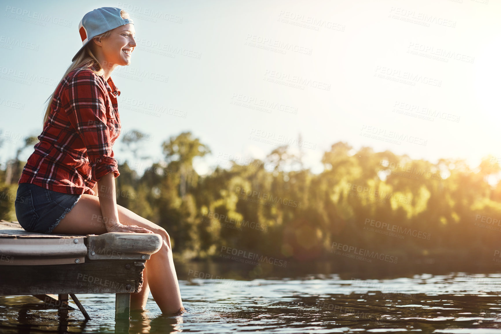 Buy stock photo Shot of a happy young woman spending time by the lakeside