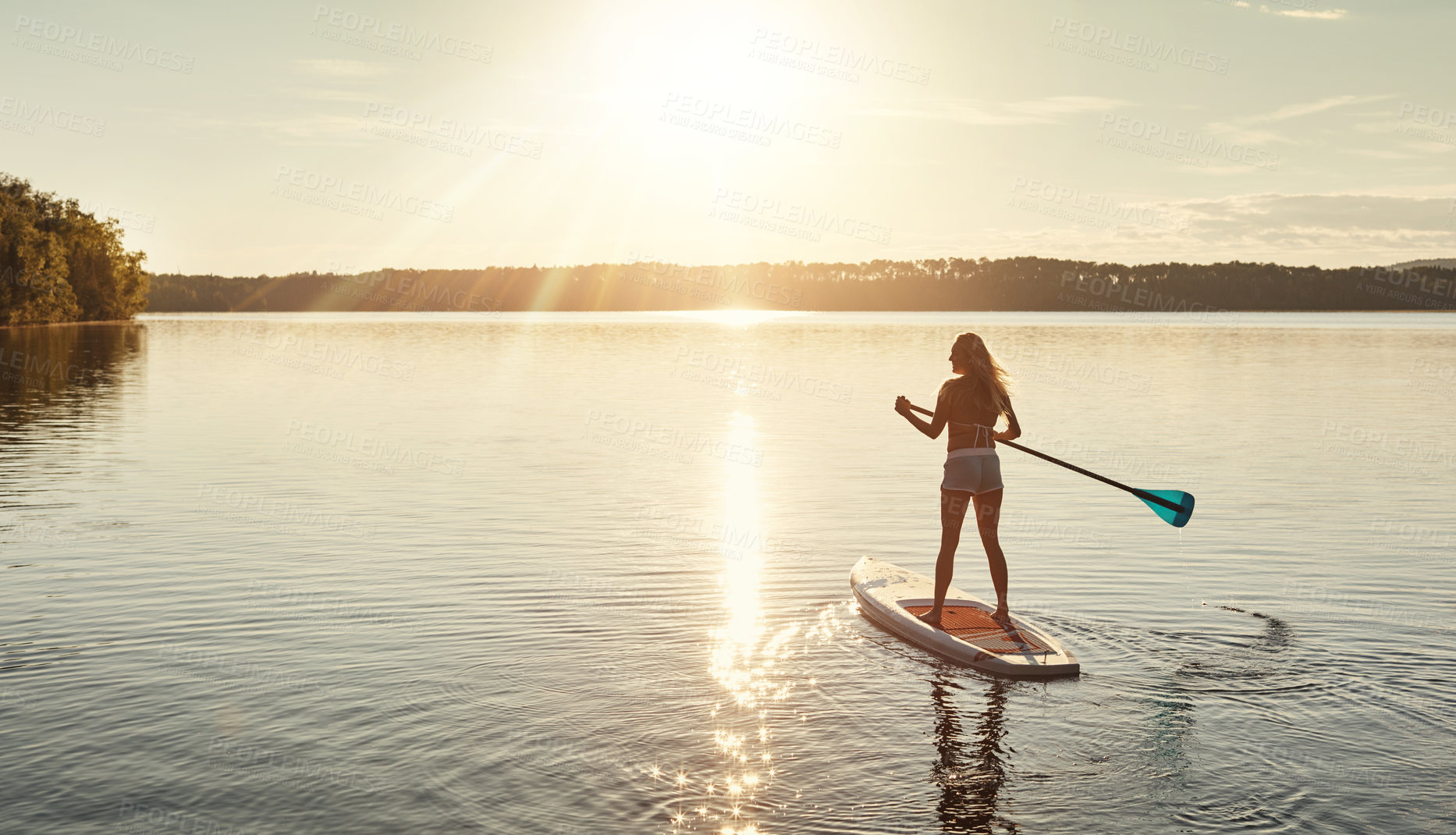 Buy stock photo Lake, sunset and woman on paddle board for relax, water sports and vacation on river for tourism. Sunshine, summer and holiday in Germany for female person, swimsuit and travel fitness for adventure