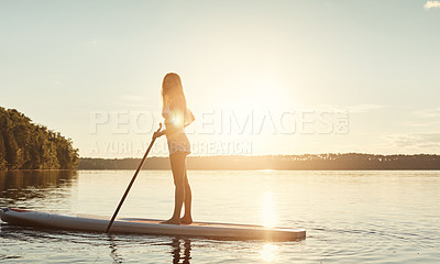 Buy stock photo Lake, sunset and woman on paddle board with sunshine, water sport and vacation on river for tourism. Exercise, summer or holiday in Germany for female person, swimsuit or travel fitness for adventure