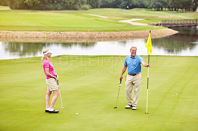 Buy stock photo Outdoor, mature couple and golf game for flag locations, challenge for sport or support with aim practice. Smile, man and woman at the club, bonding and retirement on turf course for competition