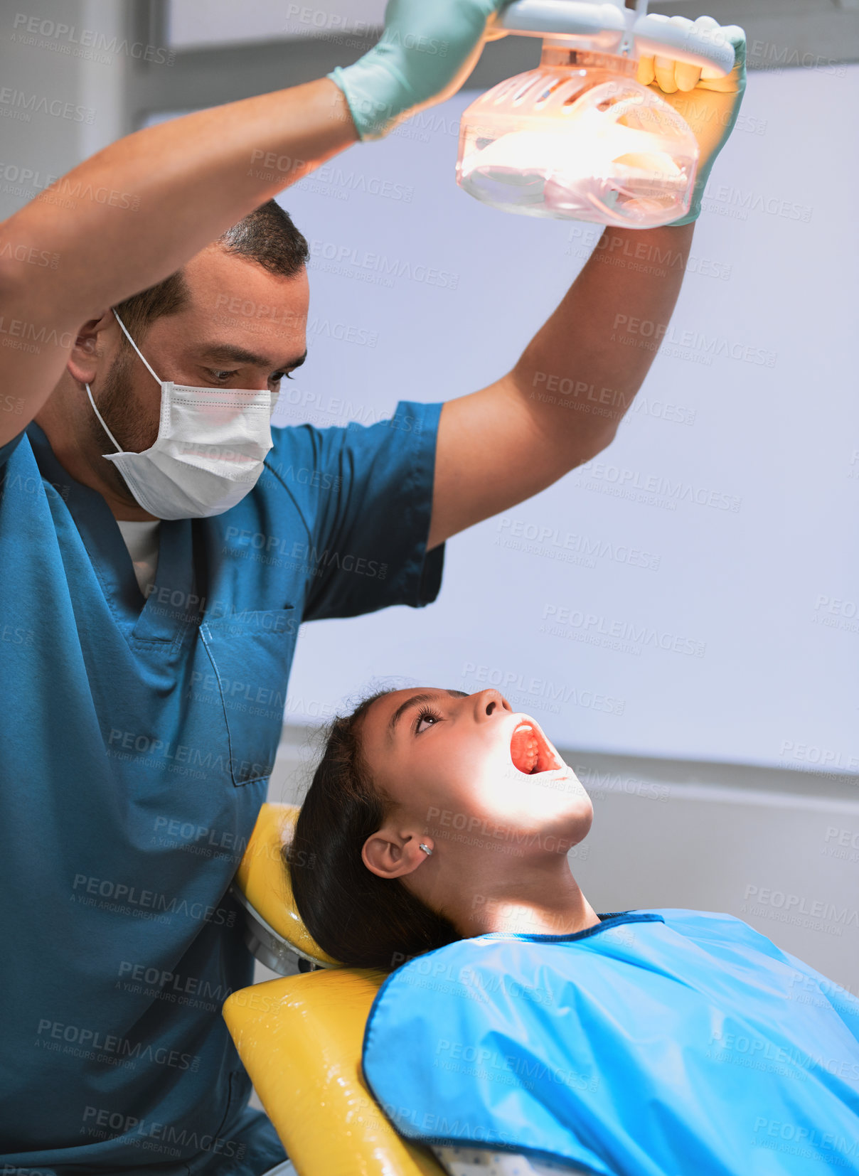 Buy stock photo Lamp, kid and dentist in consultation for teeth checkup, cleaning and oral hygiene at pediatric clinic. Girl, light and orthodontics treatment for tooth, root canal and dental health with equipment