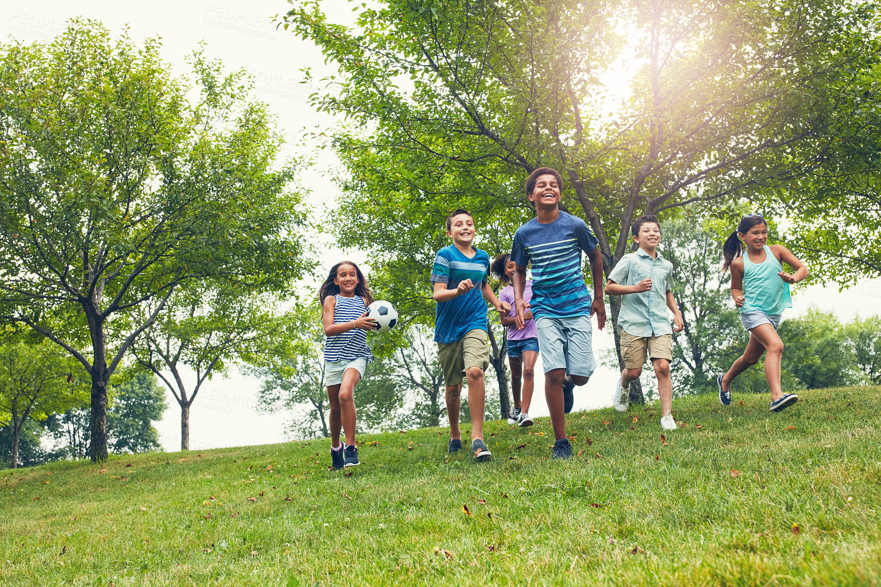 Buy stock photo Shot of a group of young friends running down an embankment in the park