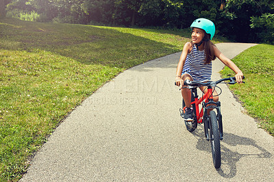 Buy stock photo Shot of a young girl out for a bicycle ride in the park