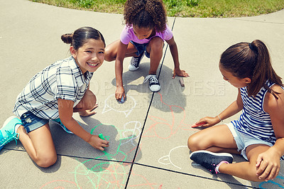 Buy stock photo Shot of adorable little girls drawing with chalk on the pavement outdoors