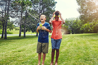 Buy stock photo Shot of adorable young boys playing with water balloons outdoors
