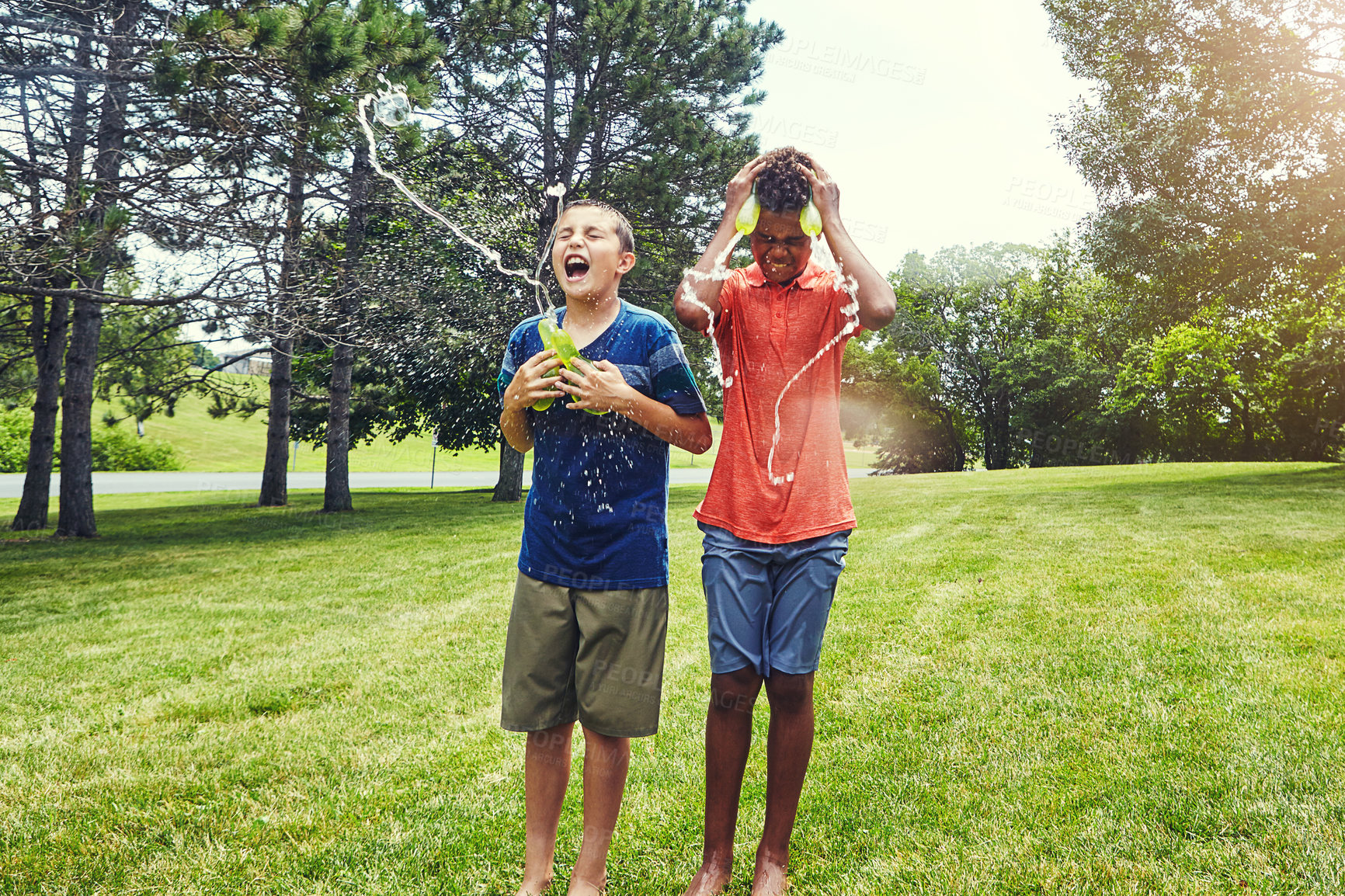 Buy stock photo Shot of adorable young boys playing with water balloons outdoors