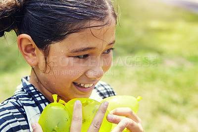 Buy stock photo Shot of an adorable little girl playing water balloons outdoors