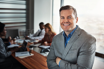Buy stock photo Portrait of a confident businessman standing in an office with his colleagues in the background