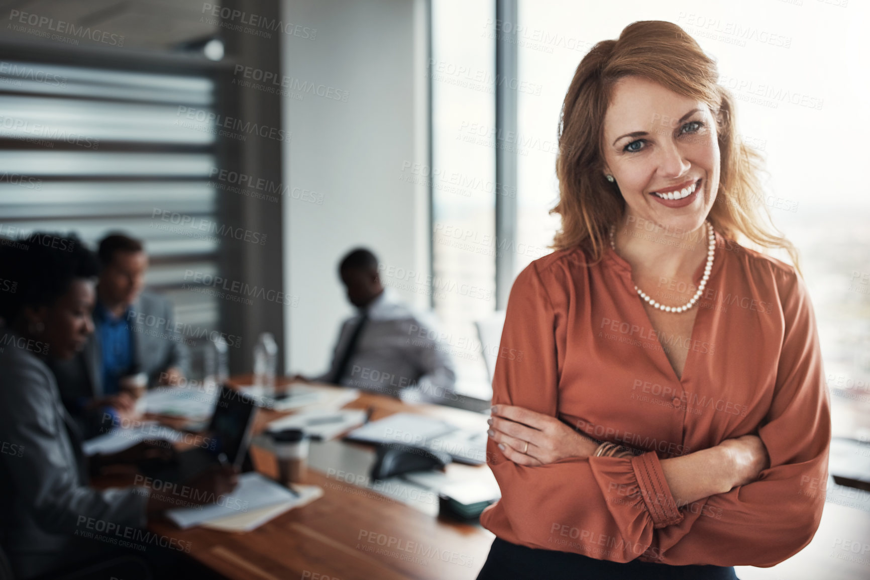 Buy stock photo Portrait of a confident young businesswoman standing in an office with her colleagues in the background