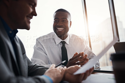 Buy stock photo Shot of two businessmen going through paperwork in an office