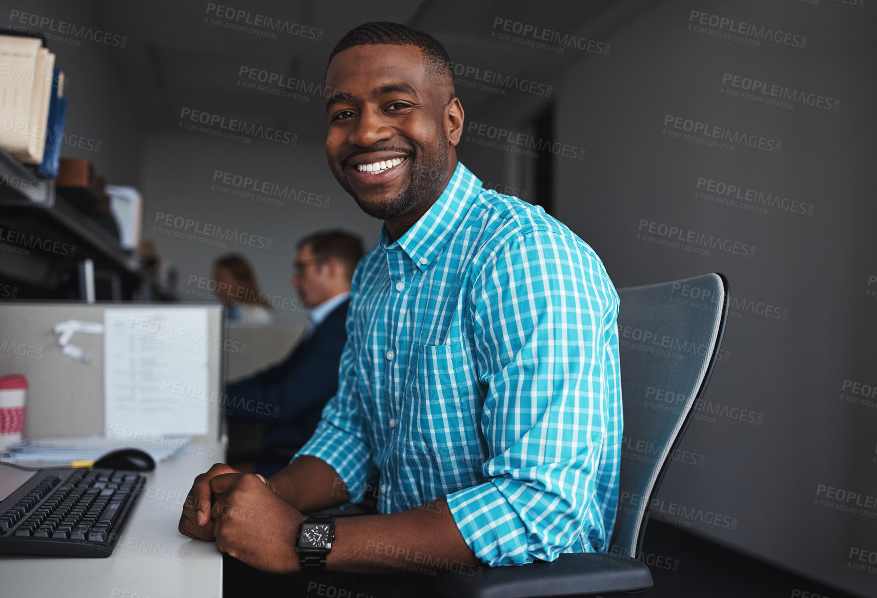 Buy stock photo Shot of a businessman sitting at his desk with colleagues in the background