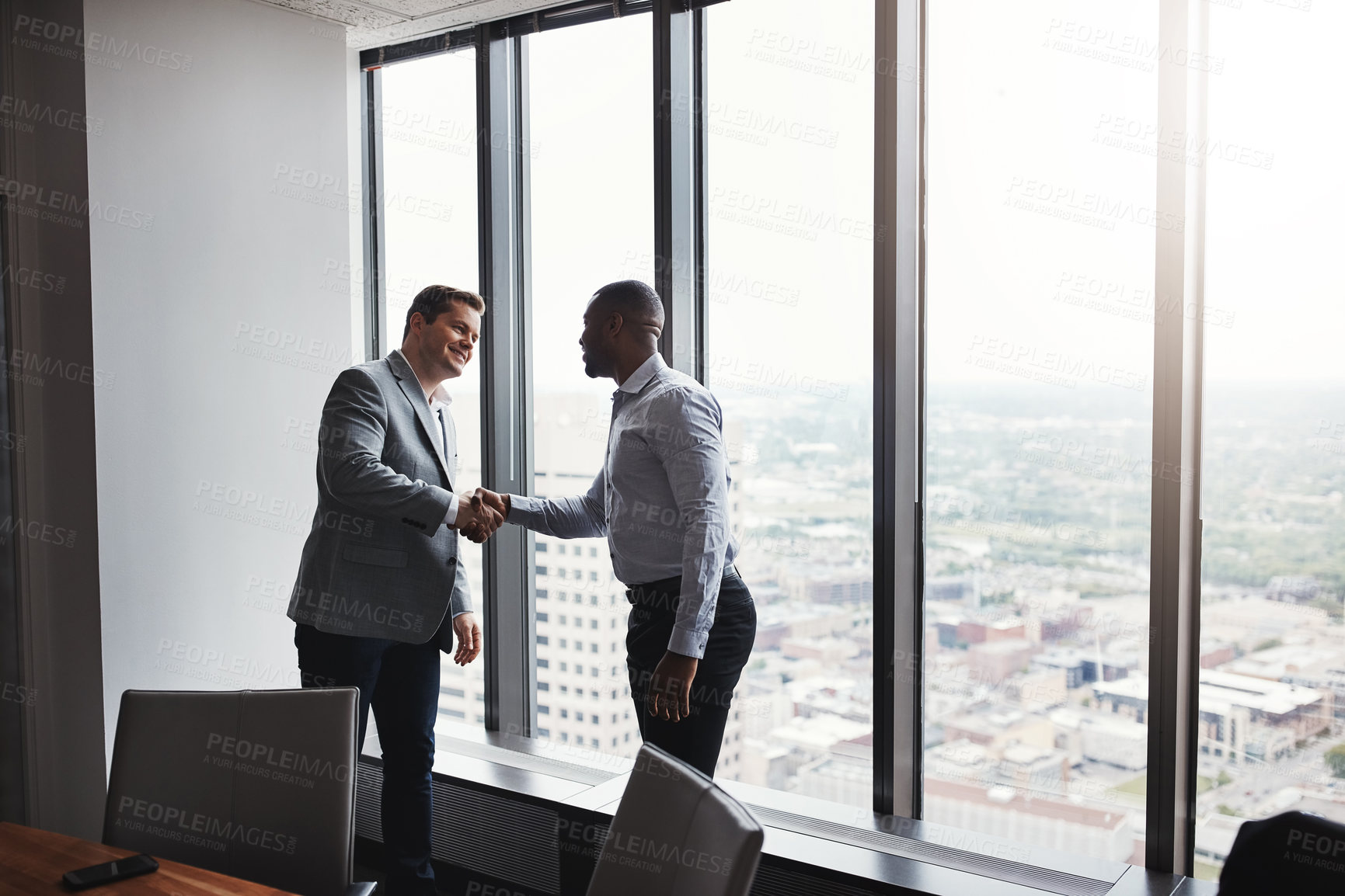Buy stock photo High angle shot of two corporate businessmen shaking hands during a meeting in the boardroom