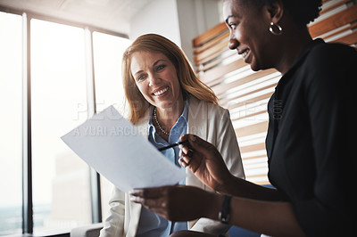 Buy stock photo Shot of two businesswomen going through paperwork in an office