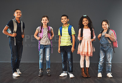 Buy stock photo Studio portrait of a diverse group of kids carrying their school backpacks against a gray background