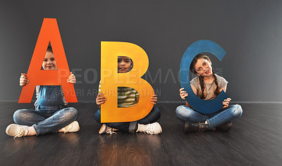 Buy stock photo Studio portrait of a diverse group of kids holding up letters of the alphabet against a gray background