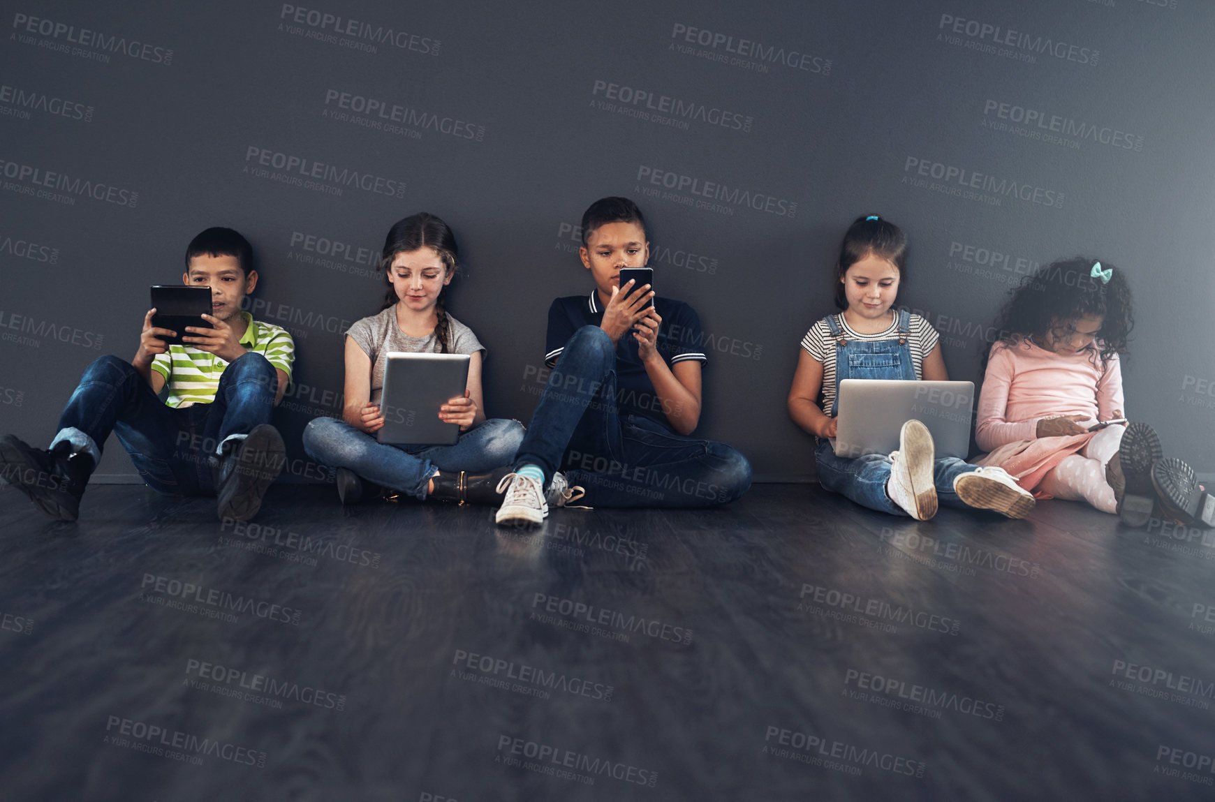 Buy stock photo Studio shot of kids sitting on the floor and using wireless technology against a gray background