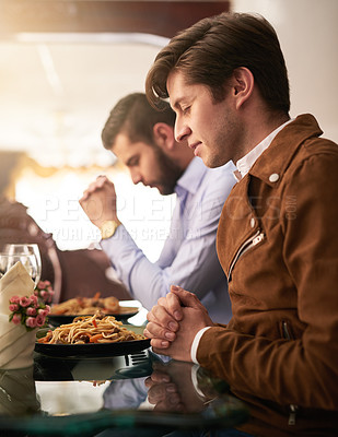 Buy stock photo Cropped shot of two young brothers saying grace during a family dinner at home