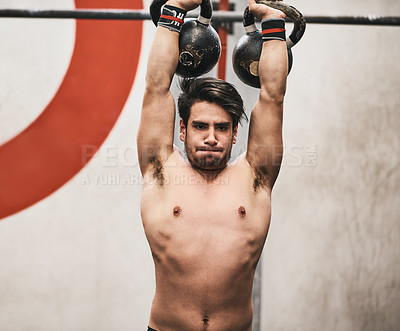 Buy stock photo Shot of a young man lifting kettlebells in a gym