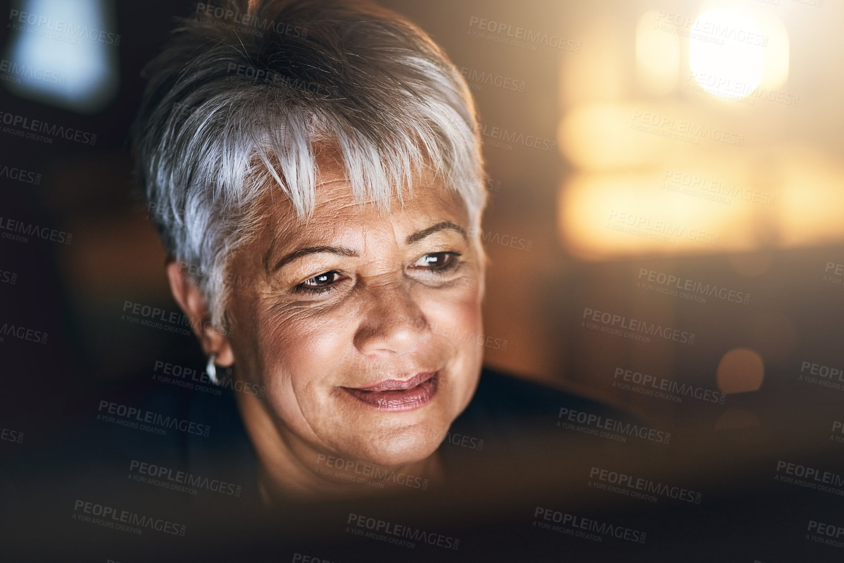 Buy stock photo Shot of a mature businesswoman using a computer during a late night at work